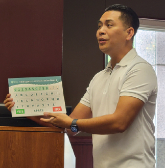 An Asian man presents a low-tech communication device at an event
