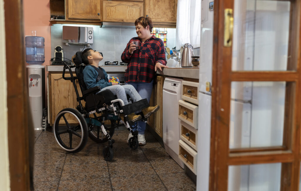 Latin mother drinking coffee in the kitchen with her disabled son. 